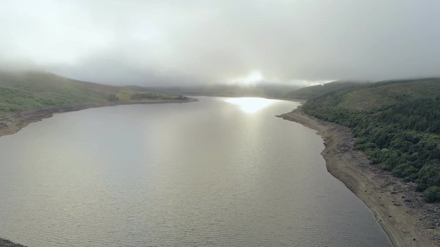 Aerial view, fast pan move. Drone panorama of Llyn Celyn water reservoir with dam and sheep on grass in Wales