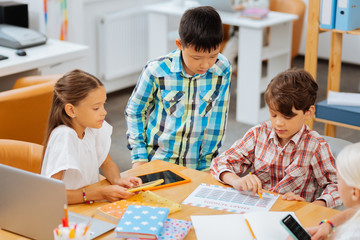 Fototapeta premium Answers. Clever smart children checking an exercise while sitting in a classroom