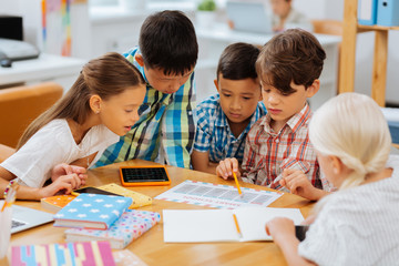 Test. Bored smart kids checking different exercises while being at school