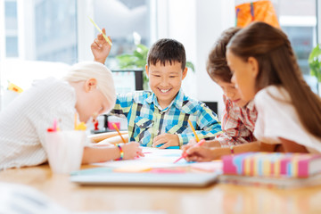 Fototapeta premium Spare time. Excited joyful kids drawing while spending time together at school