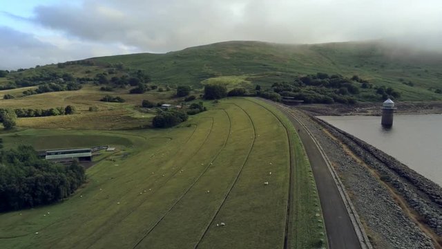 Aerial view, move down. Drone panorama of Llyn Celyn water reservoir with dam and sheep on grass in Wales