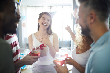 Cheerful girl saying thanks to friends for their present for her birthday at home party