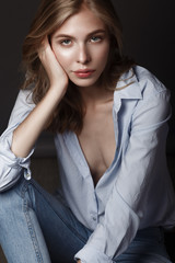 Naklejka premium fashion model with long hair, beautiful eyes, perfect skin is posing in studio for glamour test photo shoot showing different poses. Picture taken in the studio on a gray background.