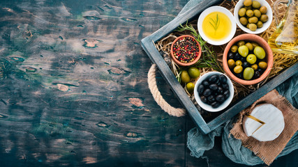 Olives, olive oil, cheese and spices. On a black wooden background. Free space for text.