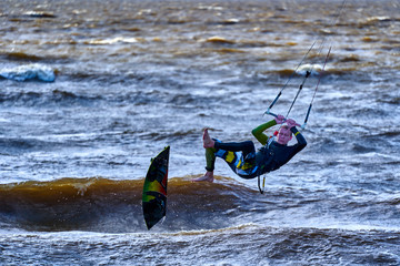A male kiteboarder jumps above the surface of the water of a large river.  Unsuccessful jump kiteboarder.