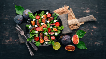 Fresh salad with figs, arugula leaves, cherry tomatoes and feta cheese. Free space for text. Top...
