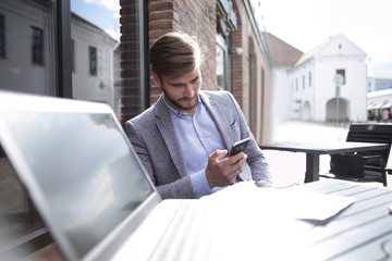 businessman with a smartphone sitting at a table in a street cafe
