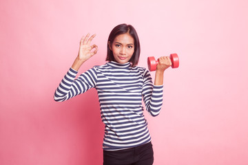 Naklejka premium Healthy Asian woman show OK with dumbbells.