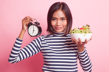 Young Asian woman with clock and salad.