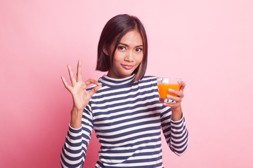 Young Asian woman drink orange juice show OK sign.