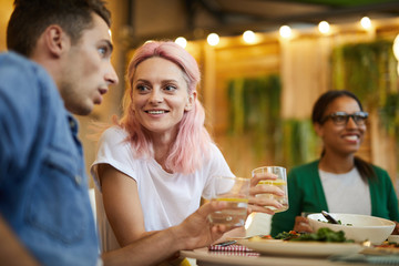 Young couple having drinks by served table at dinner in cafe and discussing something