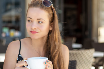 Shopping time. Happy young woman drinking a cappuccino on a terrace.