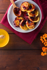 Cottage cheese pancakes on a wooden background. Syrniki with jam on a red napkin. Pancakes with cottage cheese on a white plate with honey and rowan berries. Healthy food