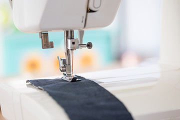 sewing machine with colour thread and needle on a table with blurred background, Tailor's work table, textile or fine cloth making, industrial fabric, home appliances tool.