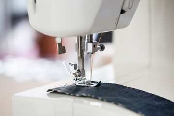 sewing machine with colour thread and needle on a table with blurred background, Tailor's work table, textile or fine cloth making, industrial fabric, home appliances tool.