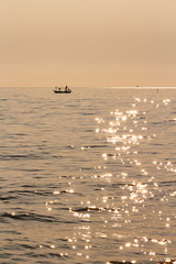 fisherman boat in beautiful calm sea with sunlight reflection on water