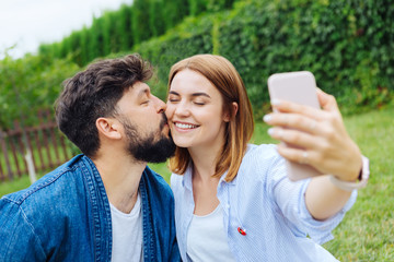 Selfie with man. Beaming blonde-haired woman feeling extremely happy while making selfie with her...