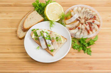 Open sandwich with pickled herring and ingredients for its preparation