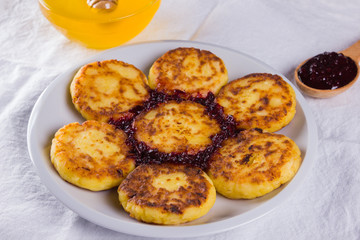 Cottage cheese pancakes on white napkin. Traditional Ukrainian dish - syrniki with jam on a wooden background. Pancakes with cottage cheese on a white plate with honey. Healthy food