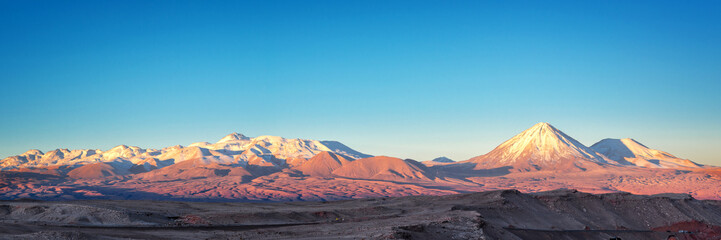 Fototapeta na wymiar Panorama of Moon Valley in Atacama desert at sunset, snowy Andes mountain range in the background, Chile