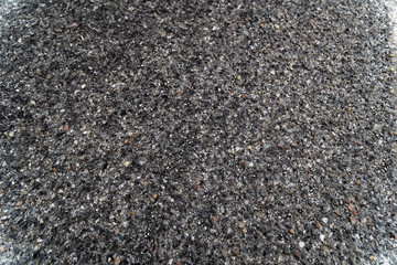 Black asphalt texture background, grainy surface.