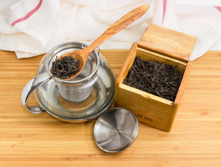 Glass teapot and tea leaves in wooden spoon and box