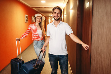 Couple with suitcases checking into the hotel - obrazy, fototapety, plakaty