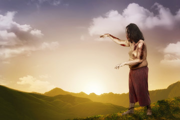 Spooky zombie man with wounded body walking around at outdoor