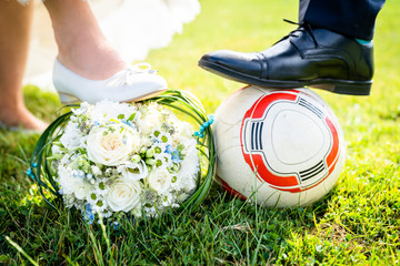 Bride and groom put their feet on the football, cool image and idea for photo shoot, wedding dress...