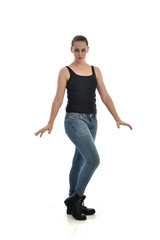 full length portrait of brunette girl wearing black single and jeans. standing pose facing the camera. isolated on white studio background.