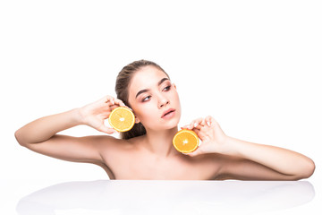Obraz na płótnie Canvas Close up beauty portrait of an excited attractive half naked woman holding orange slices at her face and looking at camera isolated over white background