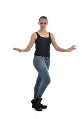 full length portrait of brunette girl wearing black single and jeans. standing pose facing the camera. isolated on white studio background.