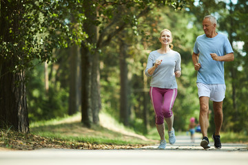 Active and healthy aged couple running in natural environment on summer morning - obrazy, fototapety, plakaty