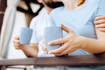 Wedding ring. Blonde-haired woman wearing nice wedding ring drinking coffee with her caring husband