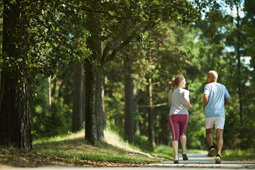 Rear view of active seniors jogging in the morning in natural environment