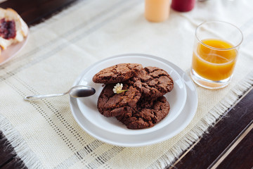 Chocolate cookies. Four chocolate cookies lying on little white plate near glass of freshly squeezed orange juice