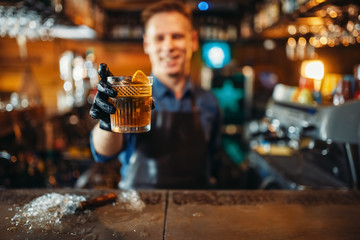 Male bartender holds out fresh alcoholic beverage