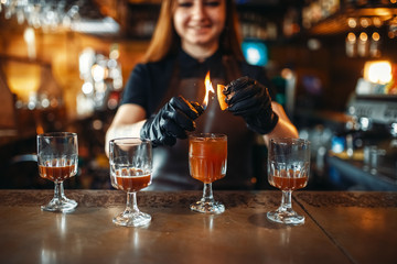 Female bartender making coctail with use of fire