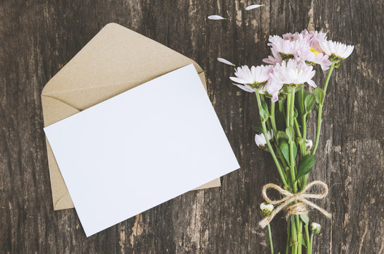 Blank Greeting Card With Brown Envelope And Mum Flowers On Wooden Table