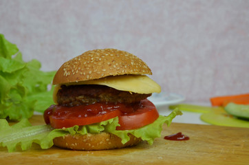 Home made hamburger with beef, onion, tomato, lettuce and cheese. Fresh burger closeup on wooden rustic table