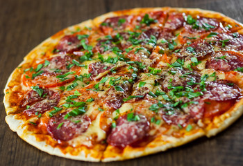 sliced Pepperoni Pizza with Mozzarella cheese, salami, Tomatoes, pepper, Spices and Fresh Basil. Italian pizza on wooden background