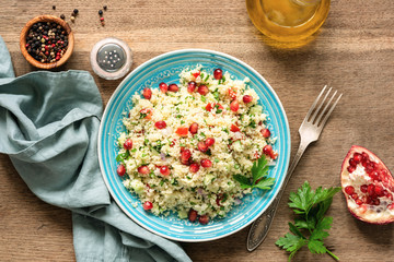Couscous salad Tabbouleh with pomegranate seeds served on traditional turquoise plate. Arabic food