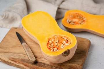 Butternut pumpkin cut in half on wooden cutting board. Preparation of pumpkin pie, pumpkin soup. Autumn comfort food cooking