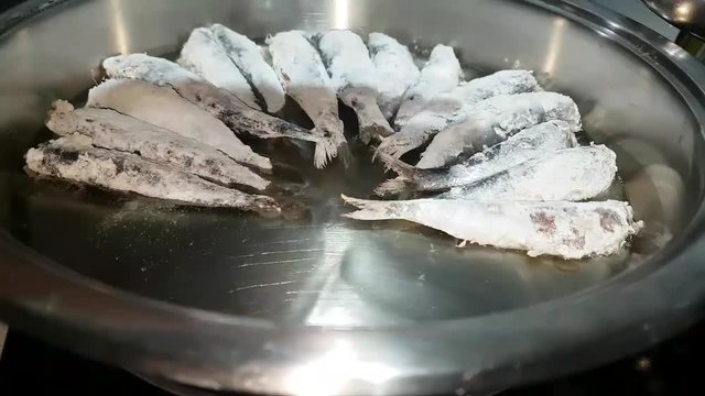 Sardine fish grilled on a pan over cooker.