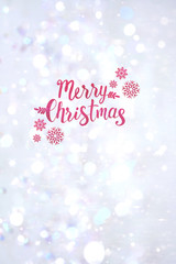 Winter snowy blurry background in light silver pink tones. Falling defocused snow with beautiful light, abstract snowflakes in blur and inscription of Merry Christmas, vertical shot, copy space.