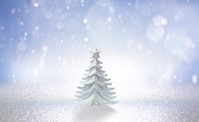 Winter christmas scenic background. Silvery small Christmas tree on blue blurred snowy defocused background with copy space.