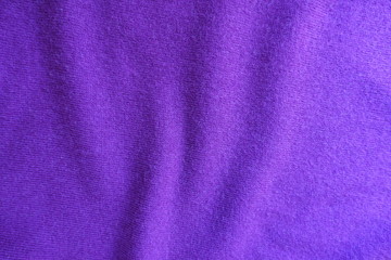 Fototapeta na wymiar Wavy folds on thin violet knitted fabric