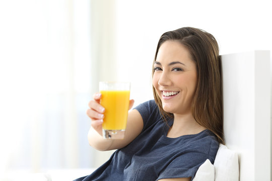 Woman on the bed showing a glass of orange juice