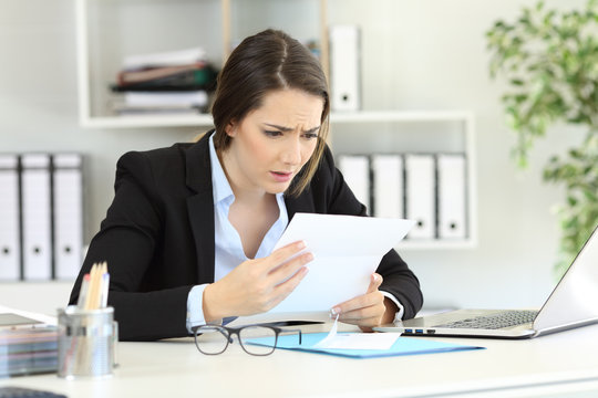 Worried office worker reading news in a letter