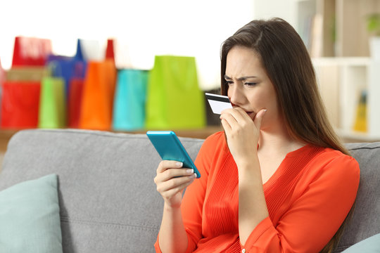 Worried lady buying online with credit card and phone